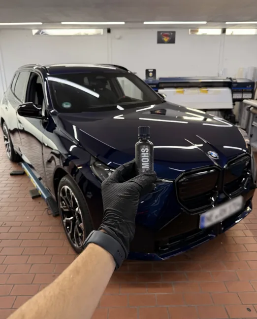 Blauer BMW mit Coating-Flasche bei Fahrzeugpflege Hannen