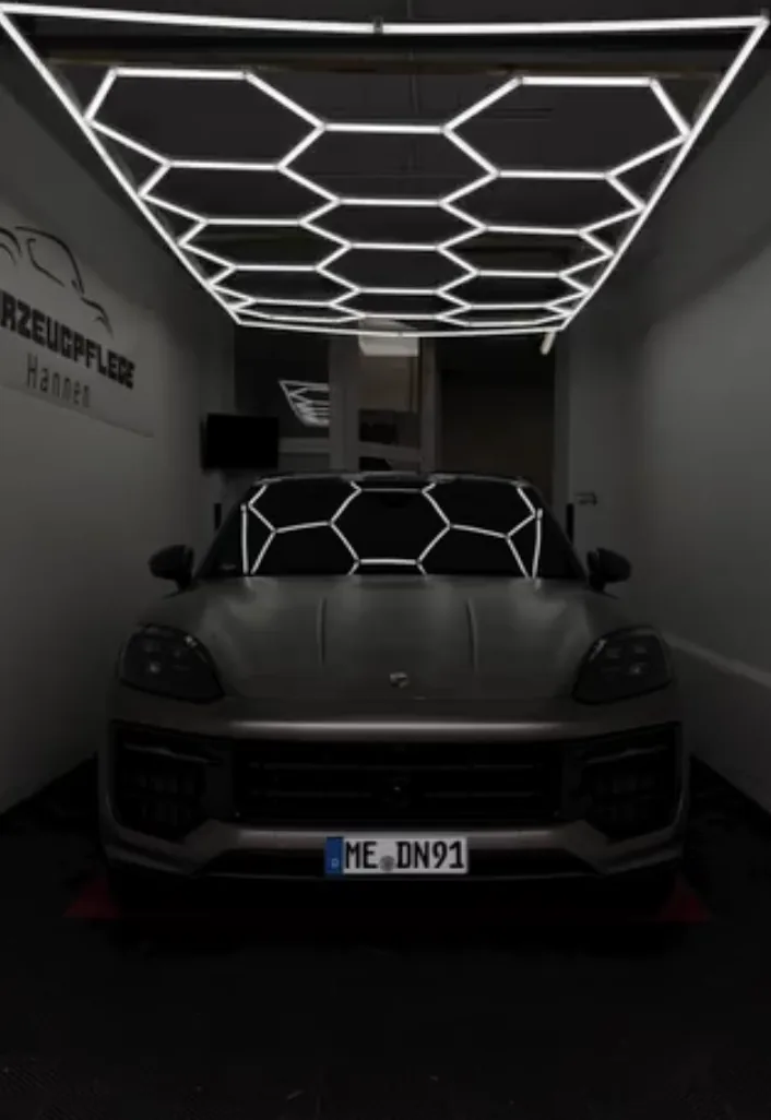 Dunkler Porsche unter Wabenlicht im Detailing-Studio